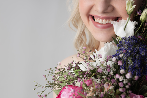 Close up of joyful young woman holding beautiful bouquet and smiling