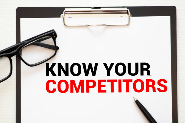istock Businessman holding a card with text KNOW YOUR COMPETITORS. Keyboard, diagram and white background 1269572544