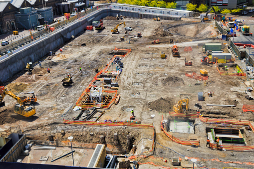 Construction site with deep excavation and machinery with workers in SYdney city - Australian Technology park.