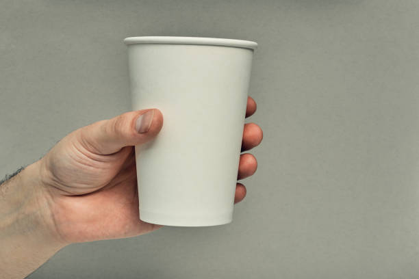 istock Paper cup in hand on a colored background. Eco-friendly materials in a coffee shop, biodegradable disposable tableware. Close up 1269580655