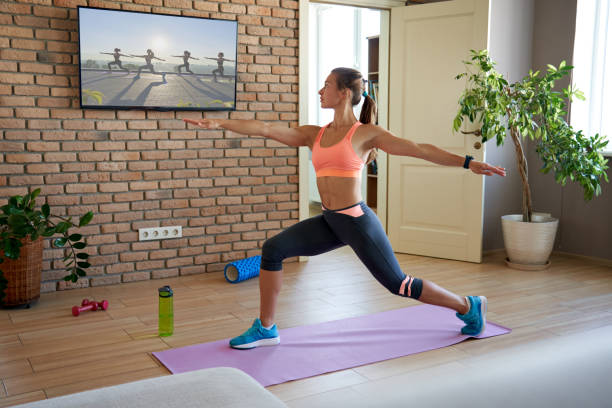 mulher em forma aprendendo yoga pose assistindo streaming de treino online na tv em casa. - yoga class instructor yoga exercising - fotografias e filmes do acervo