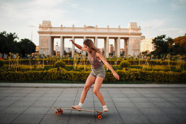 Young adult woman ride and trick on longboard skateboard in park Young sporty woman riding on the longboard in the park Ollie stock pictures, royalty-free photos & images