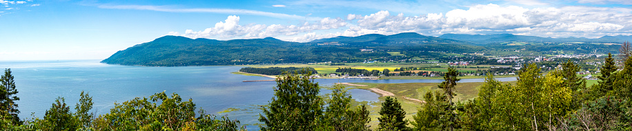 Baie-St-Paul village in Charlevoix, Quebec, Canada. High angle view with mountain Massif de Charlevoix (sky resort) in background. View of St-Lawrence river. Summer photography.