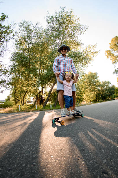 istock young man with little girl practicing skateboarding in park. 1269604986