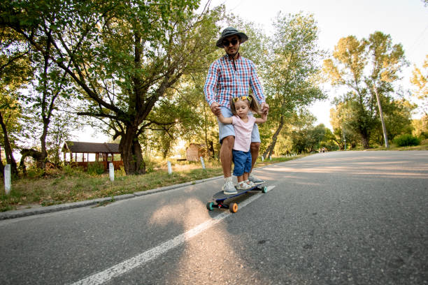 istock young man with little child practicing skateboarding in park. 1269605045