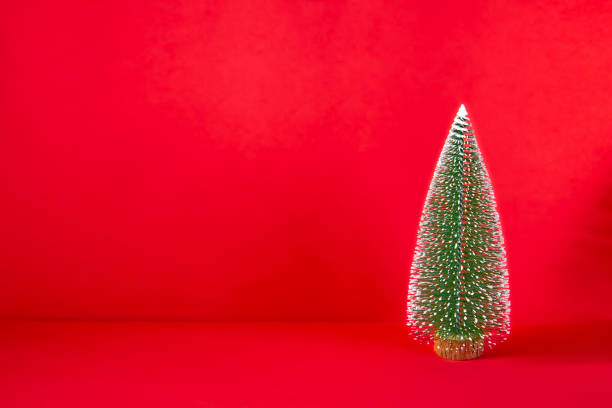 istock Small Christmas tree on red background and copy space for text 1269608782