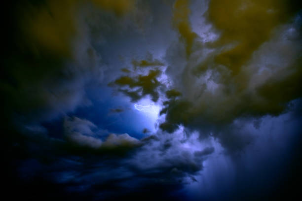 Looking straight up into a cloud at the beginning moment of a lightning strike in blue atmosphere partially obscured by clouds