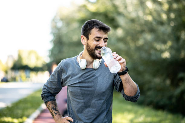 istock The young man takes a break during training, gets tired and drinks water on a treadmill 1269635301