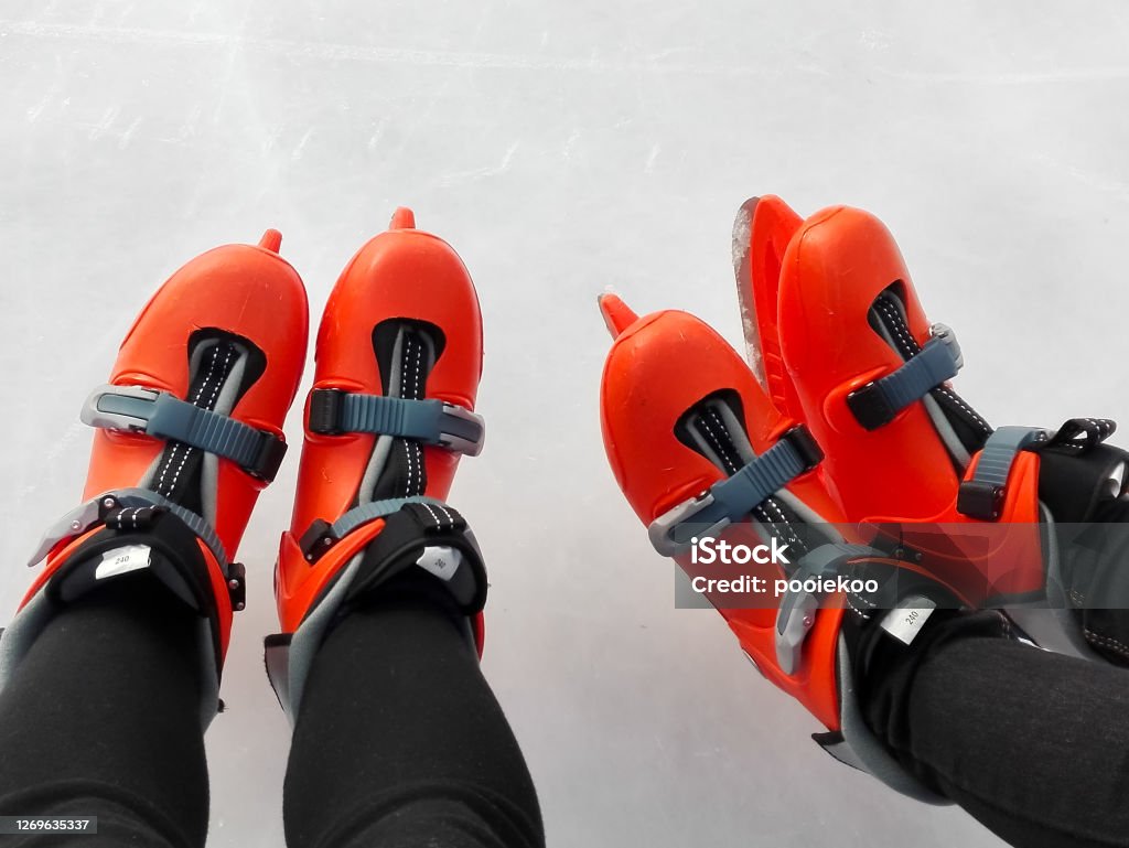 Orange Ice Stake Shoes on Ice Surface, Two Pairs Two Pairs of Orange Ice Stake Shoes on Ice Hockey Stock Photo