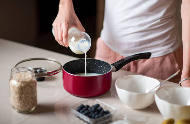 istock Woman adding milk while making morning breakfast oatmeal cereals in the kitchen at home 1269642691