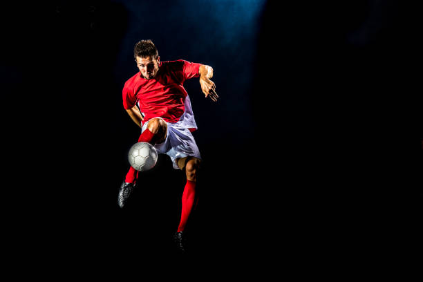 istock Soccer player kicking the ball on black background. 1269652765
