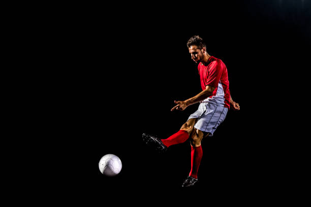 istock Soccer player kicking the ball on black background. 1269652766