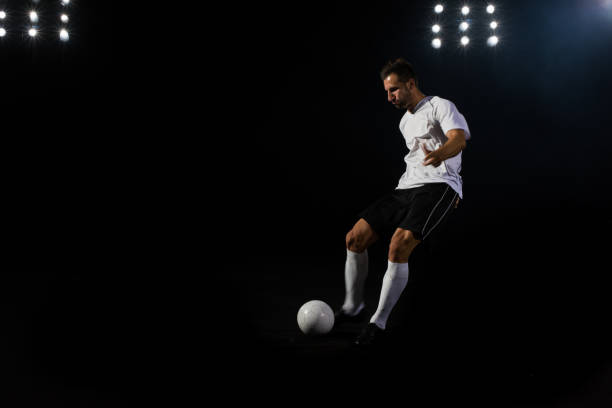 istock Soccer player kicking the ball against a black background 1269652772