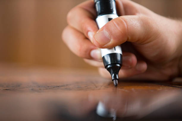 Close-up of a Man Writing or Drawing on Wooden Table With Permanent Marker Close-up of a Man Writing or Drawing on Wooden Table With Permanent Marker. permanent marker stock pictures, royalty-free photos & images