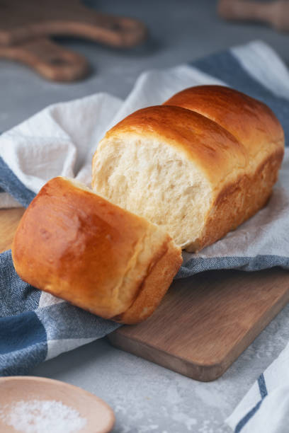 Fresh-baked homemade Hokkaido milk bread on the kitchen towel. Japanese soft and fluffy bread. Cooking at home. Selective focus. stock photo