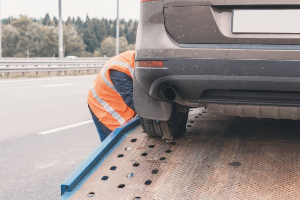 istock Tow truck with worker towing a broken down car on the highway 1269656118