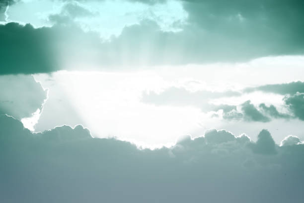 Dramatic sky with stormy clouds penetrated by rays of rising sun as silver lining.