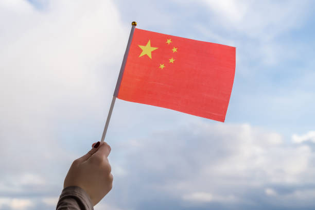 istock Woman hand with Chinese swaying flag on sunset sky. Concept 1269656193