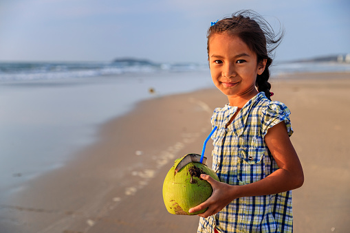 Vietnamese girl holding coconut on the beach, Vietnam