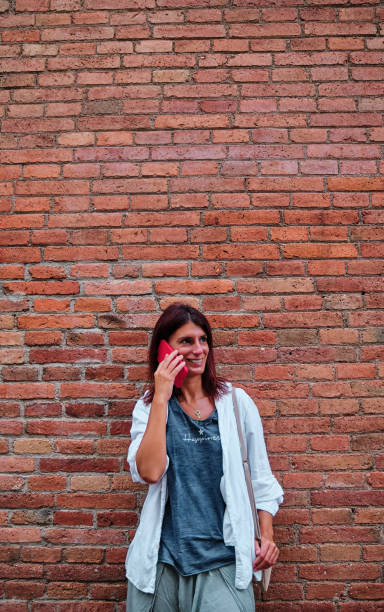 istock adult woman using mobile phone with brick wall behind 1269665304