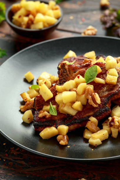 istock Roasted Pork chops with caramelized apples, walnuts and sage in black plate on wooden table 1269665492