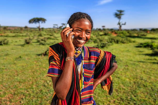 femme africaine utilisant un téléphone portable, village près de yabelo, éthiopie - global village photos et images de collection