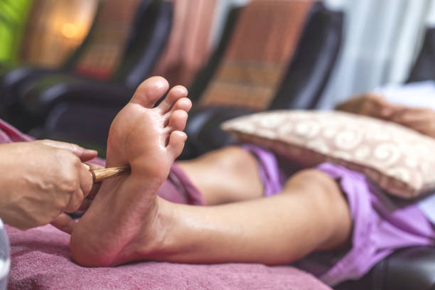 le massage thaï des pieds est un mélange de massage des pieds et de réflexologie. pied d’acupression - reflexology human foot physical therapy massaging photos et images de collection