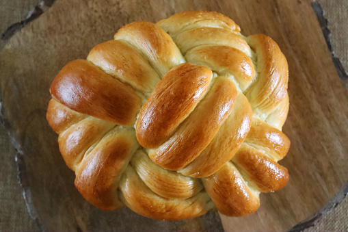 Stock photo showing a close-up view of loaf of traditional Jewish ceremonial bread, braided challah loaf made from white flour.