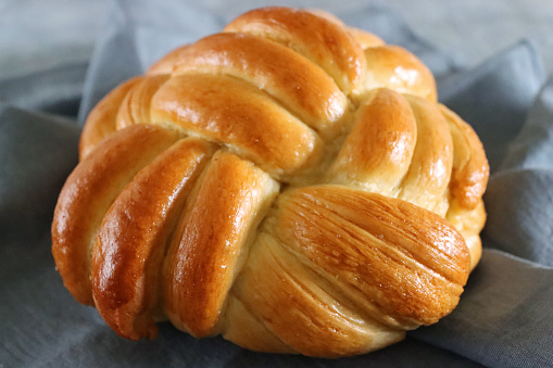 Stock photo showing a close-up view of loaf of traditional Jewish ceremonial bread, braided challah loaf made from white flour.
