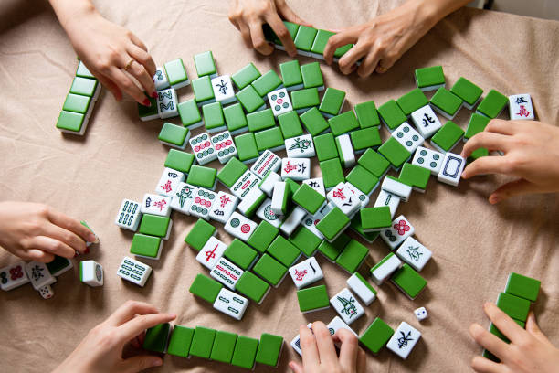istock People mixing tiles while playing Chinese board game Mahjong at home 1269668652