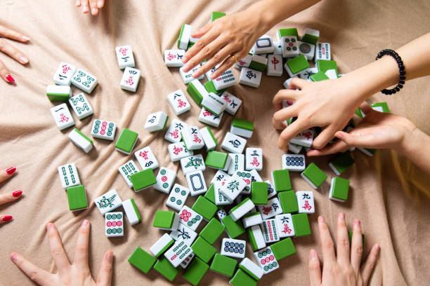 istock People mixing tiles while playing Chinese board game Mahjong at home 1269668725