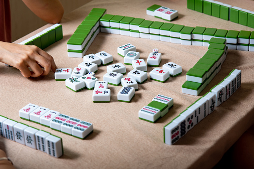 Women playing Chinese board game Mahjong at home. Fun and leisure with friends, domestic life in Asia