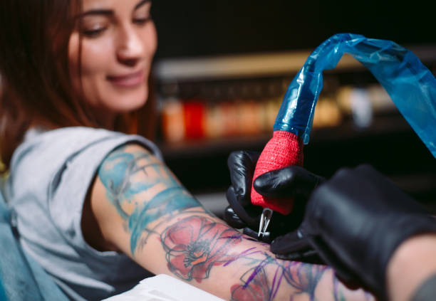 Professional tattoo artist makes a tattoo on a young girl's hand. stock photo