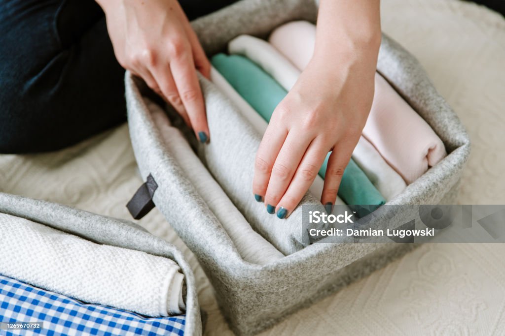 Folding clothes and organizing stuff in boxes and baskets. Concept of tidiness, minimalist lifestyle and japanese t-shirt folding system. Wardrobe storage system. Clean up clothes with konmari method (Marie Kondo) Organization Stock Photo