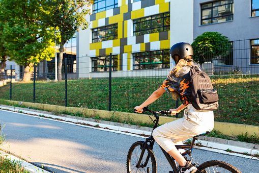 Teenage girl going to school.She riding bicycle and wearing protective mask and helmet.