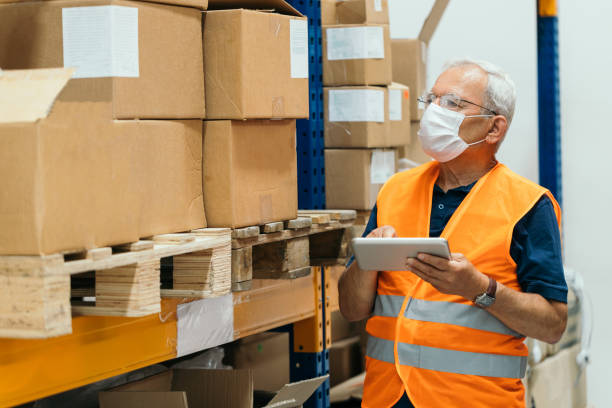 istock Senior manager wearing  protective face mask, using digital tablet and checking medical stock  in a warehouse 1269675860