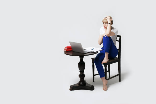 istock Surprised or stressed young female student sitting at desk working or studying remotely online on laptop. Distant learning or remote work from home. Isolated on white background. 1269677015