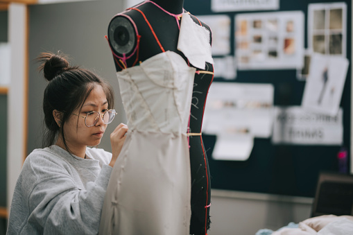 asiática china mujer moda estudiante universitario haciendo proyecto de ropa en el taller de la universidad photo
