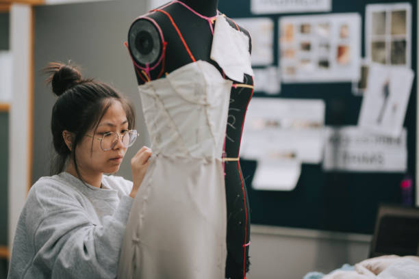 asian chinese female fashion college student doing clothing project at college workshop asian chinese female fashion college student doing clothing project at college workshop fashion designer photos stock pictures, royalty-free photos & images