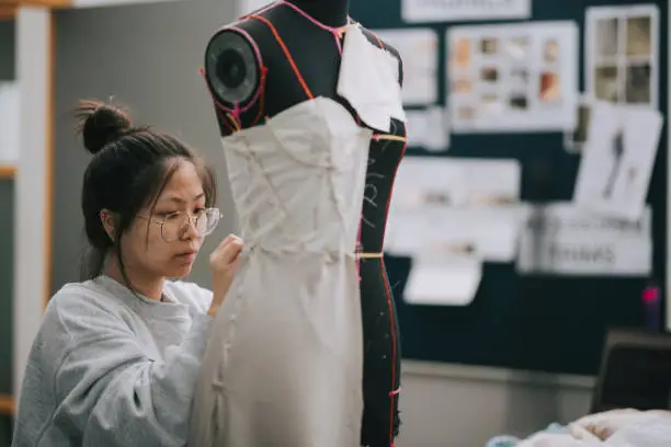 Photo of asian chinese female fashion college student doing clothing project at college workshop
