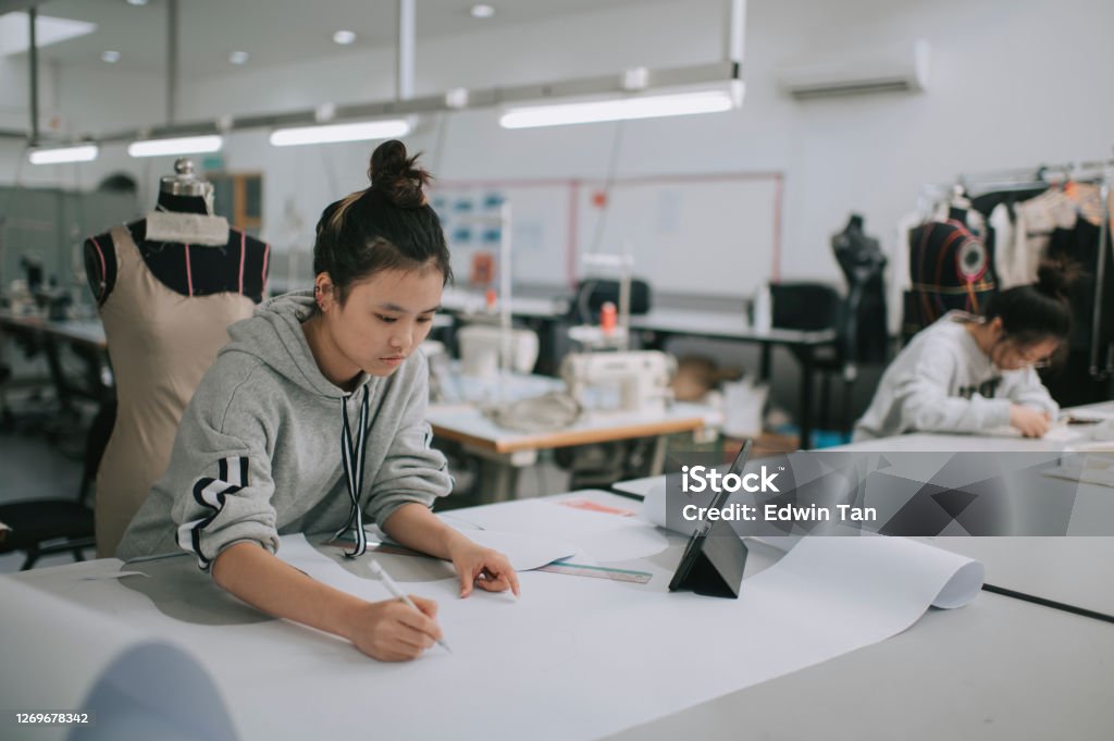 asian chinese female fashion college student writing down measurement and drawing sewing pattern doing clothing project at college workshop asian chinese female fashion college student doing clothing project at college workshop Fashion Stock Photo