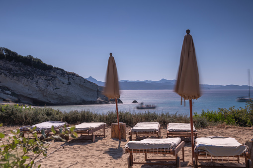A relaxing spot with wooden furniture on the beach and the Mediterranean sea in the background