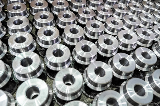 batch of shiny round steel parts background, close-up with selective focus and blur.