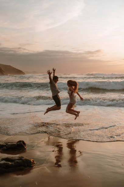 Young couple jumping at a beach and having fun stock photo