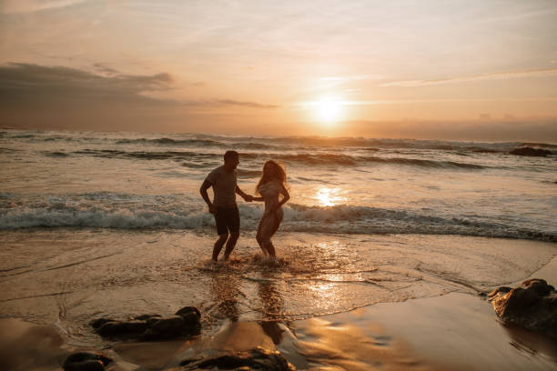 istock Young couple jumping at a beach and having fun 1269684993