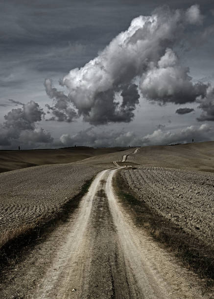 istock Road between fields in the Tuscan countryside, with big cloud 1269686993