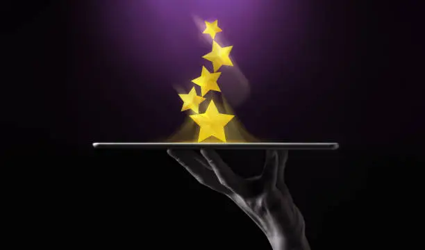 Photo of Success in Business or Personal Talent Concept. Hand Raise Up a Digital tablet with Golden Five Star Awards