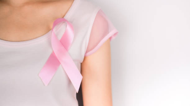 白い背景の白いtシャツを着た女性の左胸にピンクのリボン、乳がんのシンボル、乳がん啓発月間。10月の重要な日 - space to left ストックフォトと画像