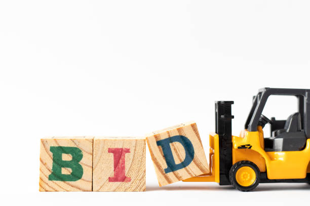 Toy forklift hold wood letter block D to complete word bid on white background Toy forklift hold wood letter block D to complete word bid on white background capital letter photos stock pictures, royalty-free photos & images