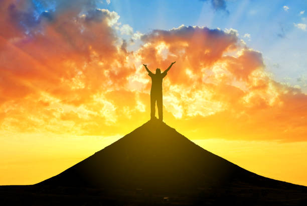 istock happy man silhouette with hands rising up stay on a mount top on a dramatic sunset background 1269688675